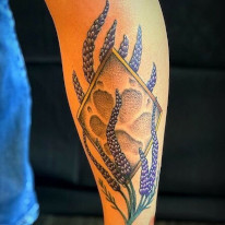 Color tattoo of a paw print surrounded by lupins. 